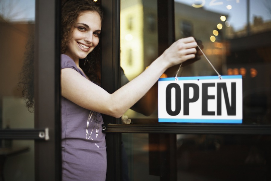 Small business owner with open sign on door