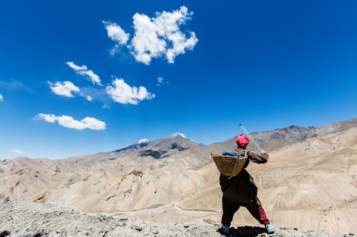 Woman slinging stones into a canyon in Ladakh, India 