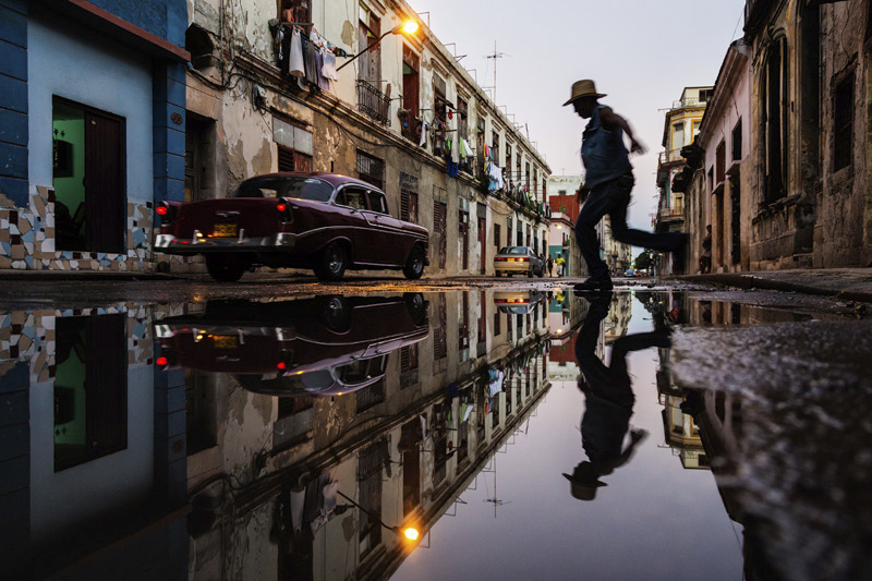 Man jumping over puddle in street in Havana, Cuba